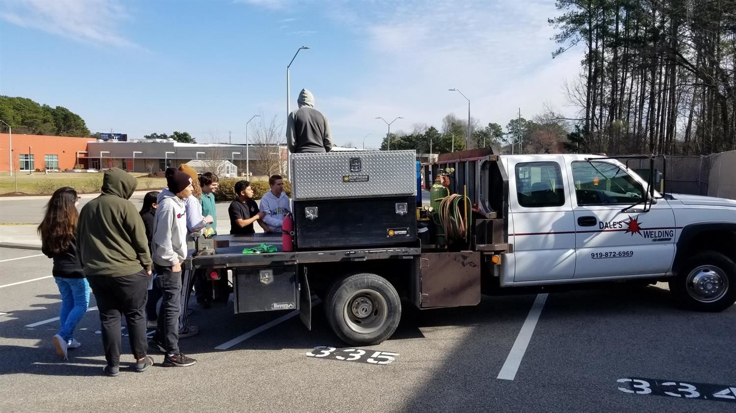 Welding speaker talking to group by truck